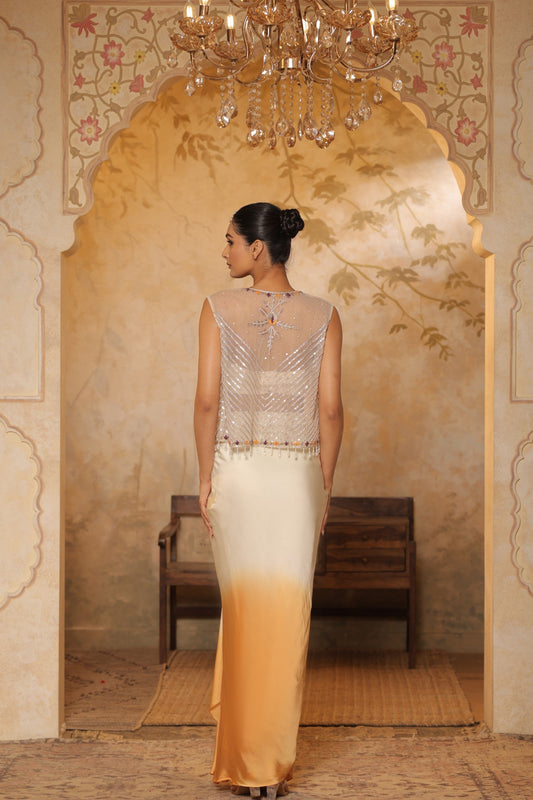 Woman in a beaded top and gradient dress standing in an ornate room with a chandelier. Ivory orange skirt dress, hand embroidered crepe outfit, elegant festive wear, designer ethnic attire, premium traditional ensemble, Sunanta Madaan, near me, Mumbai, Delhi, Hyderabad, Bangalore, Pune