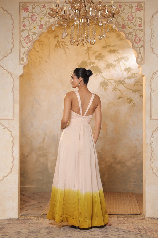 Woman in a white and yellow dress standing in an ornate room with a chandelier. Ivory yellow jumpsuit, satin organza outfit, sequin work haldi wear, premium festive attire, elegant designer jumpsuit, Sunanta Madaan, Mumbai, Delhi, Hyderabad, Bangalore, Pune