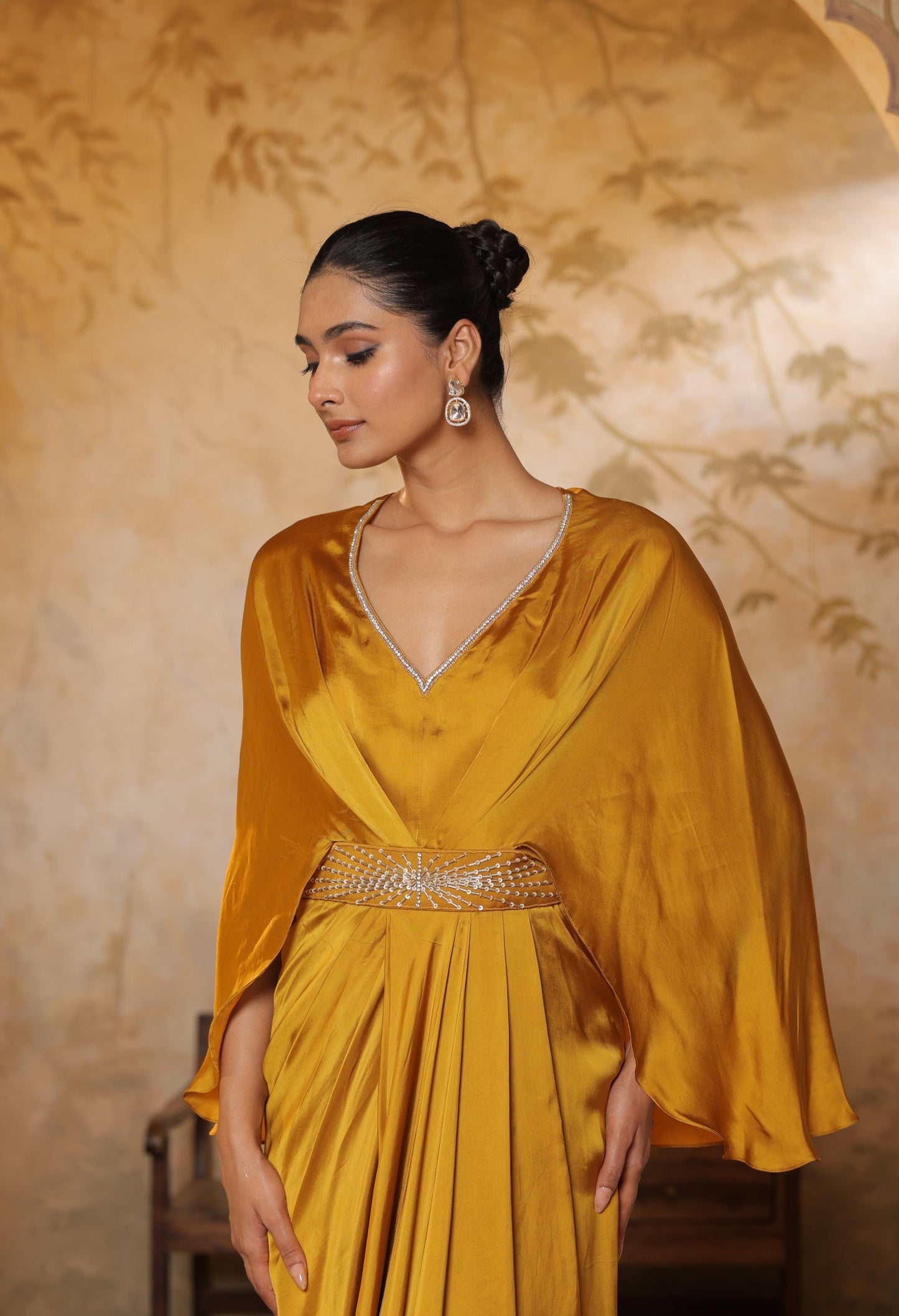Woman wearing a mustard yellow dress with a textured background. Yellow crepe kaftan, V-neck embroidered kaftan, handcrafted festive outfit, elegant ethnic wear, designer party kaftan, Sunanta Madaan