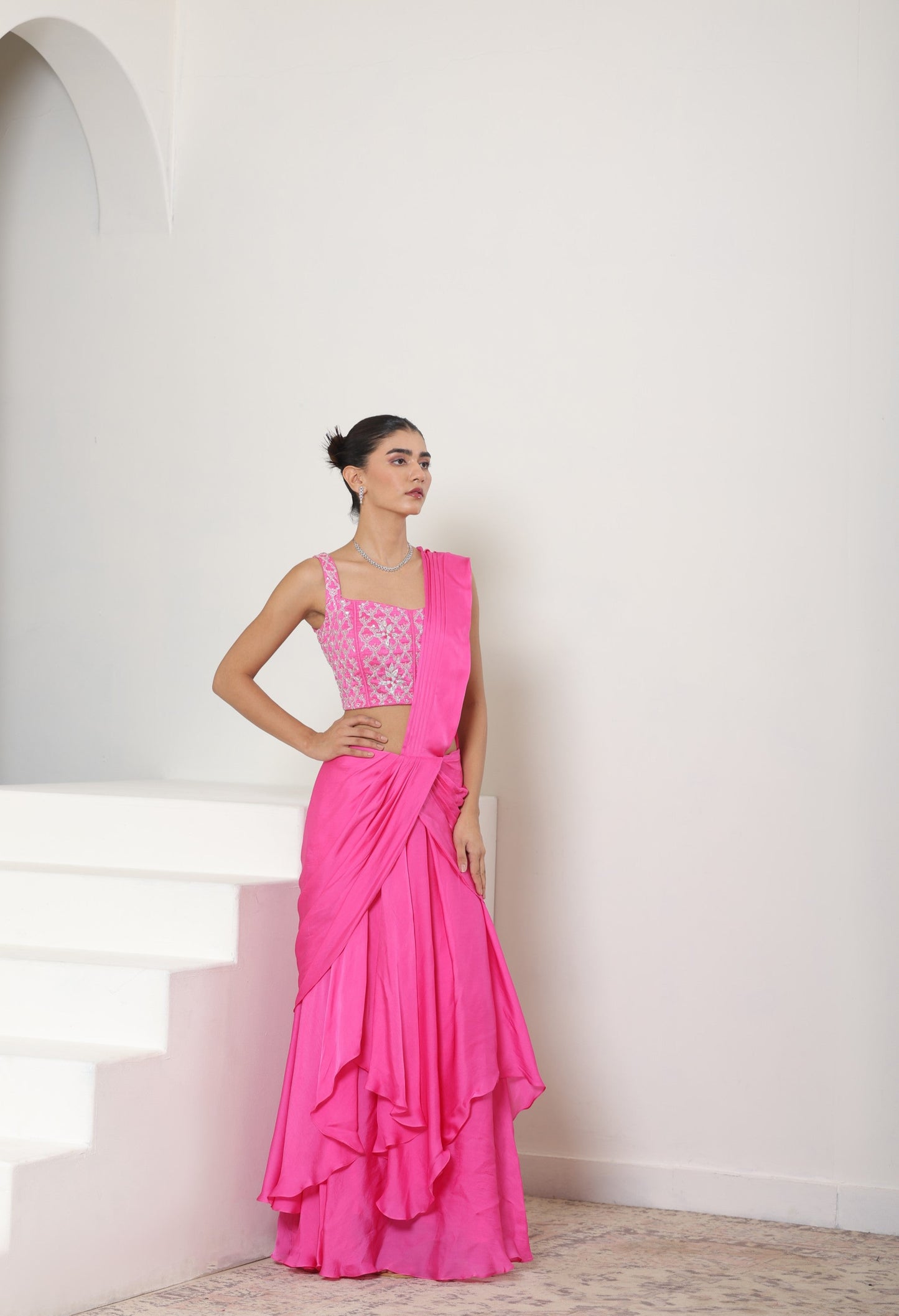 Woman wearing a bright pink saree with a white background; Pink satin organza saree, premium sangeet saree, embroidered designer saree, elegant festive wear, party ready saree, Sunanta Madaan