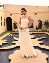 Graceful ivory sharara set featuring a lace corset, perfect for Diwali celebrations. The ensemble includes a stunning strapless corset blouse, offering a chic and modern twist to traditional style. Ideal for a destination wedding, this sharara set combines elegance and sophistication for any special occasion. Explore this unique sharara with corset blouse for a glamorous look. Sunanta Madaan