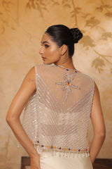 Woman wearing a beaded blouse with intricate designs against a beige background; ivory georgette saree, saree with embroidered cape, designer wedding saree India, Indo Western bridal outfit, elegant ivory saree, Sunanta Madaan