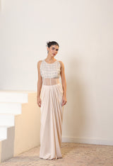 Woman wearing a white lace top and beige skirt standing on a staircase. Sunanta Madaan – Ivory Crepe Satin Western Embroidered Gown, Premium Cocktail Wear, Elegant Party Outfit, Boho Indo-Western Dress, Indo-Western Fusion Wear, Women’s Formal Evening Dress, Indo-Western Outfit for Reception, Party Outfit, Indo-Western Draped Dress, Jaipur, Delhi, Hyderabad, Ahmedabad, Bangalore, near me