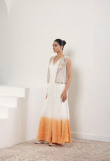 Woman wearing a long, gradient dress with a white top and orange bottom in a minimalistic setting. Ivory orange jumpsuit, satin organza outfit, designer cape jumpsuit, elegant occasional wear, festive ethnic attire, Sunanta Madaan, near me, Mumbai, Delhi, Hyderabad, Bangalore, Pune