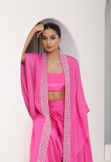 Woman wearing a pink traditional outfit with a white border against a white background; Hot pink sharara set, embroidered crepe outfit, handcrafted evening wear, elegant festive attire, designer party ensemble, Sunanta Madaan