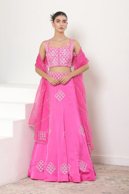 Woman wearing a pink traditional outfit with white embroidery on a light background; Pink satin organza lehenga, embroidered designer outfit, premium reception wear, elegant festive attire, traditional bridal ensemble, Sunanta Madaan, Boho Indo-Western dress, Indo-Western fusion wear, Indo-Western attire for engagement, Indo-Western outfit for sangeet, Indo-Western draped dress, Indo-Western embroidered skirt, Indo-Western embroidered dress, near me, Mumbai, Delhi, Hyderabad, Bangalore, Pune