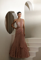 Woman in a pink evening gown standing in a modern interior setting. Sunanta Madaan – Mocha Mousse Crepe Embroidered Drape Lehenga Saree, Premium Festive Wear, Elegant Party Outfit, Boho Indo-Western Dress, Indo-Western Fusion Wear, Indo-Western Attire for Engagement, Indo-Western Outfit for Sangeet, Indo-Western Draped & Embroidered Skirt, Women’s Designer Festive Ensemble, Delhi, Jaipur, Hyderabad, Ahmedabad, Bangalore, near me