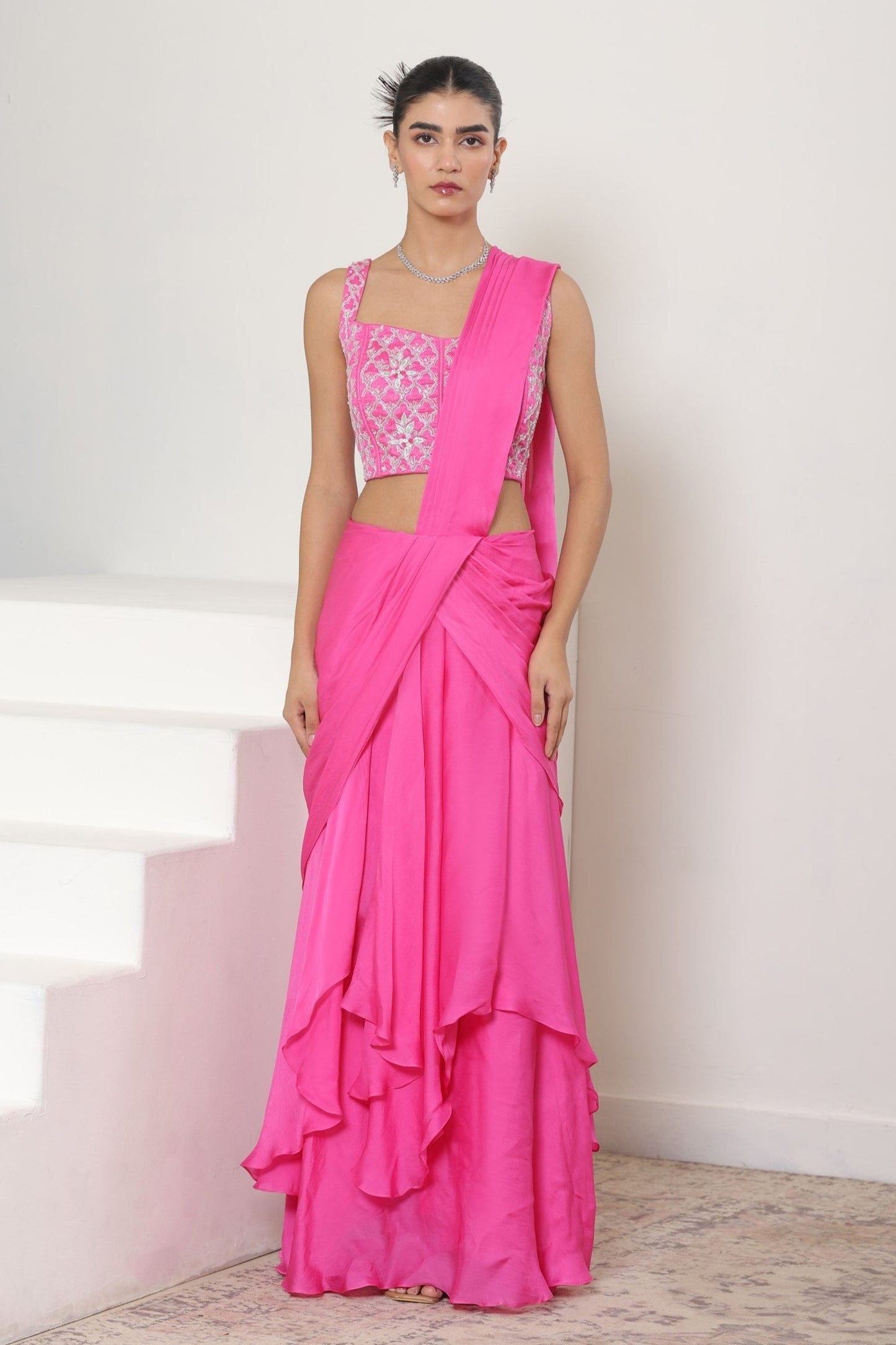 Woman wearing a bright pink saree with a white blouse on a white background; Pink satin organza saree, premium sangeet saree, embroidered designer saree, elegant festive wear, party ready saree, Sunanta Madaan