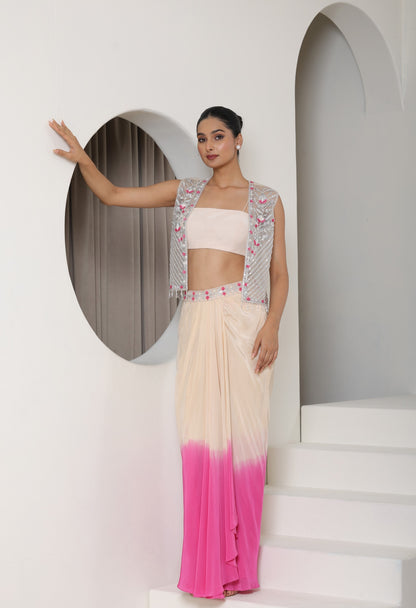 Woman in a pink and white outfit with a gradient skirt, standing against a white wall with an arch. Ivory pink skirt dress, viscose crepe outfit, pre-draped designer wear, premium occasion attire, elegant festive ensemble, Sunanta Madaan, near me, Mumbai, Delhi, Hyderabad, Bangalore, Pune