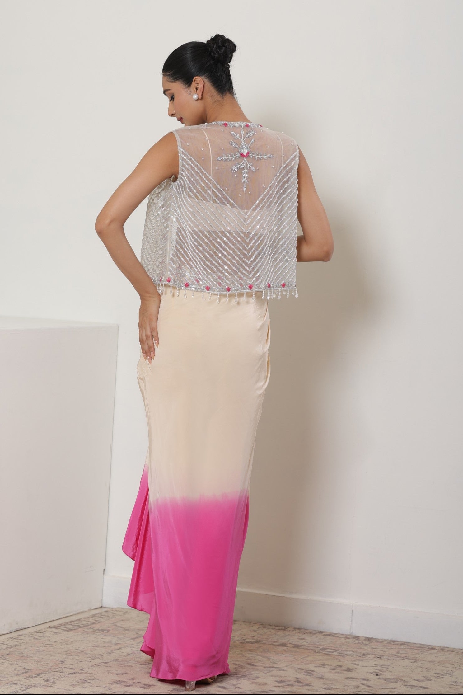 Woman wearing a sleeveless top and pink to white gradient skirt against a plain background; Ivory pink skirt dress, viscose crepe outfit, pre-draped designer wear, premium occasion attire, elegant festive ensemble, Sunanta Madaan, near me, Mumbai, Delhi, Hyderabad, Bangalore, Pune