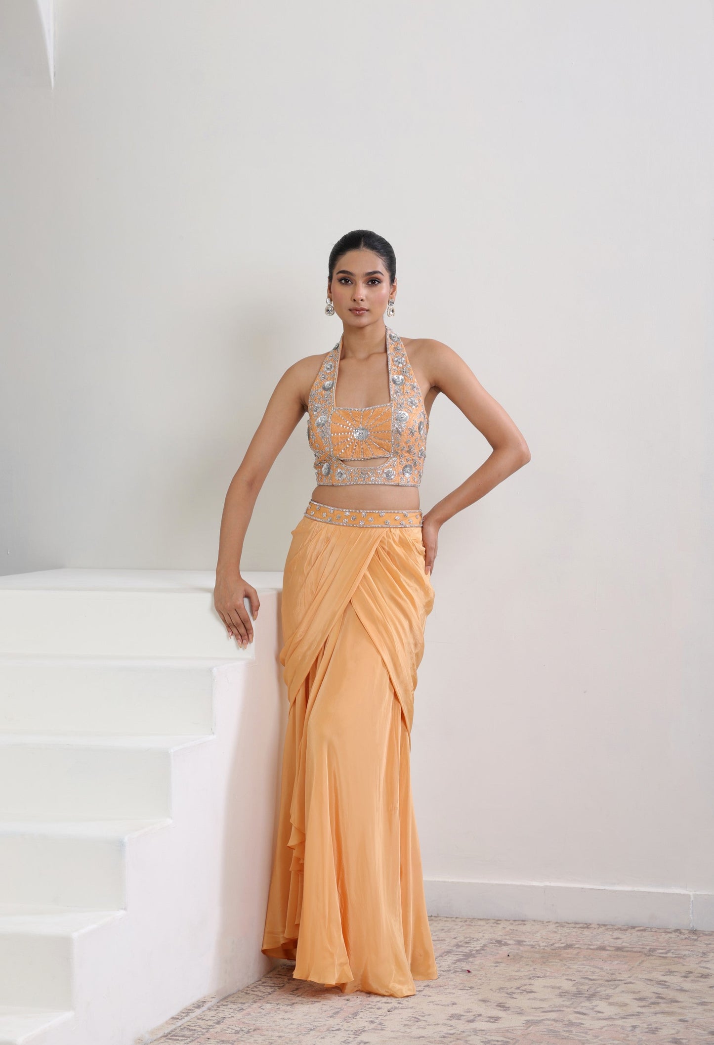 Woman wearing a peach-colored saree with a matching blouse against a white background; Orange viscose crepe skirt set, premium festive outfit, elegant ethnic wear, designer traditional attire, handcrafted party ensemble, Sunanta Madaan, near me, Mumbai, Delhi, Hyderabad, Bangalore, Pune