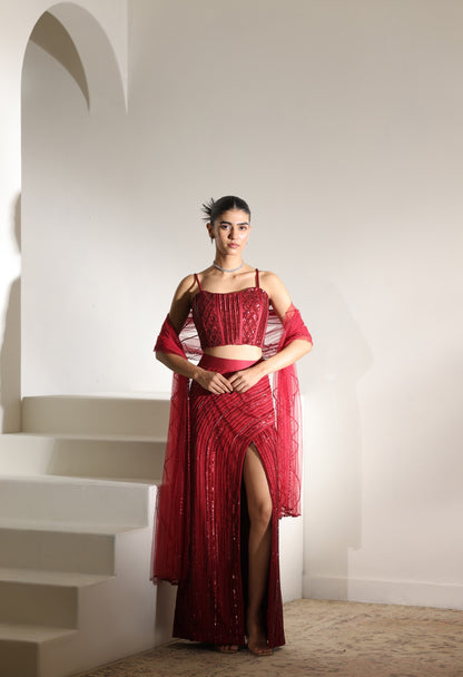 Woman in a red dress standing on a staircase with a white wall background; Sunanta Madaan – Burgundy Satin Embroidered Western Skirt Set, Handcrafted Festive Wear, Elegant Party Outfit, Boho Indo-Western Dress, Indo-Western Fusion Wear, Indo-Western Attire for Engagement, Indo-Western Outfit for Sangeet, Indo-Western Draped & Embroidered Skirt, Women’s Designer Festive Ensemble, Mumbai, Jaipur, Hyderabad, Ahmedabad, Pune, near me