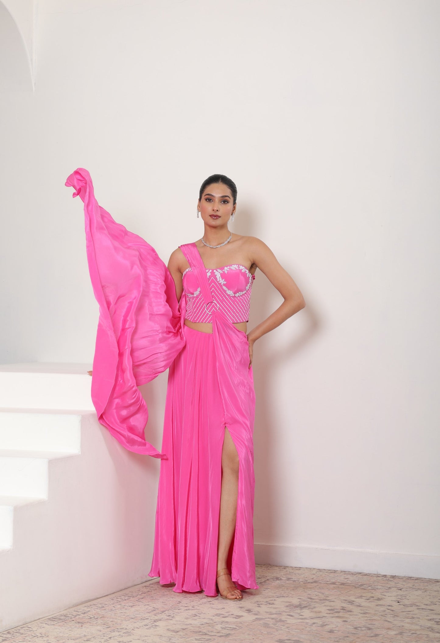 Woman in a bright pink saree with a white background; Hot pink crepe saree, hand embroidered saree, premium cocktail outfit, elegant evening wear, designer festive saree, Sunanta Madaan