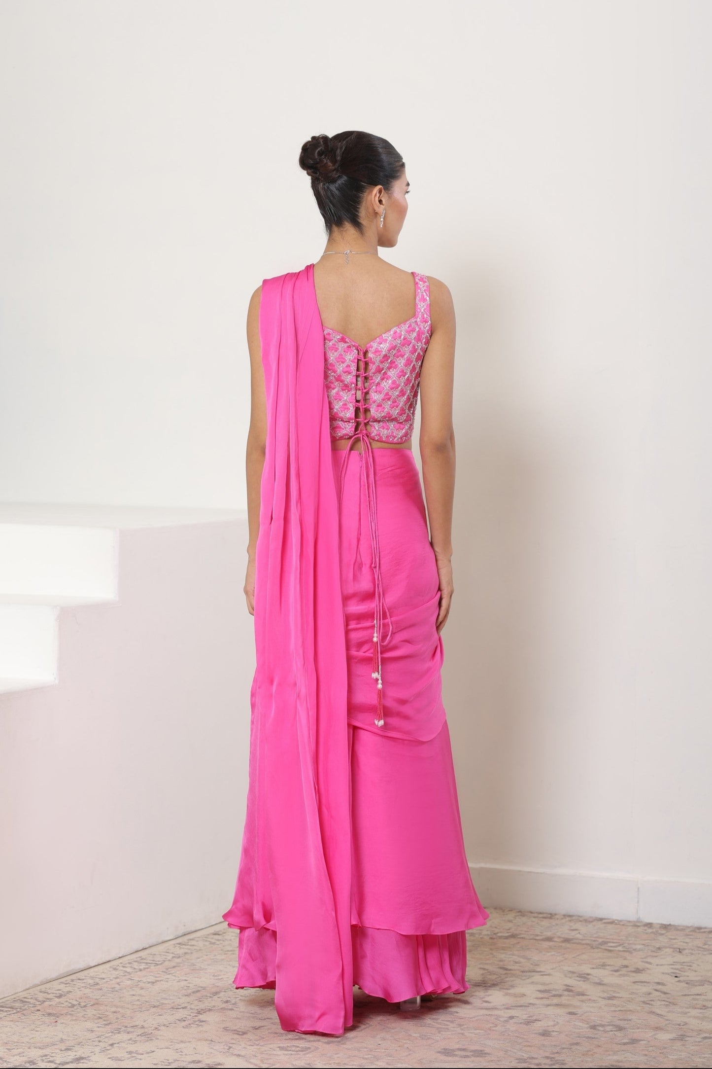 Woman wearing a pink saree with a matching blouse against a white background; Pink satin organza saree, premium sangeet saree, embroidered designer saree, elegant festive wear, party ready saree, Sunanta Madaan