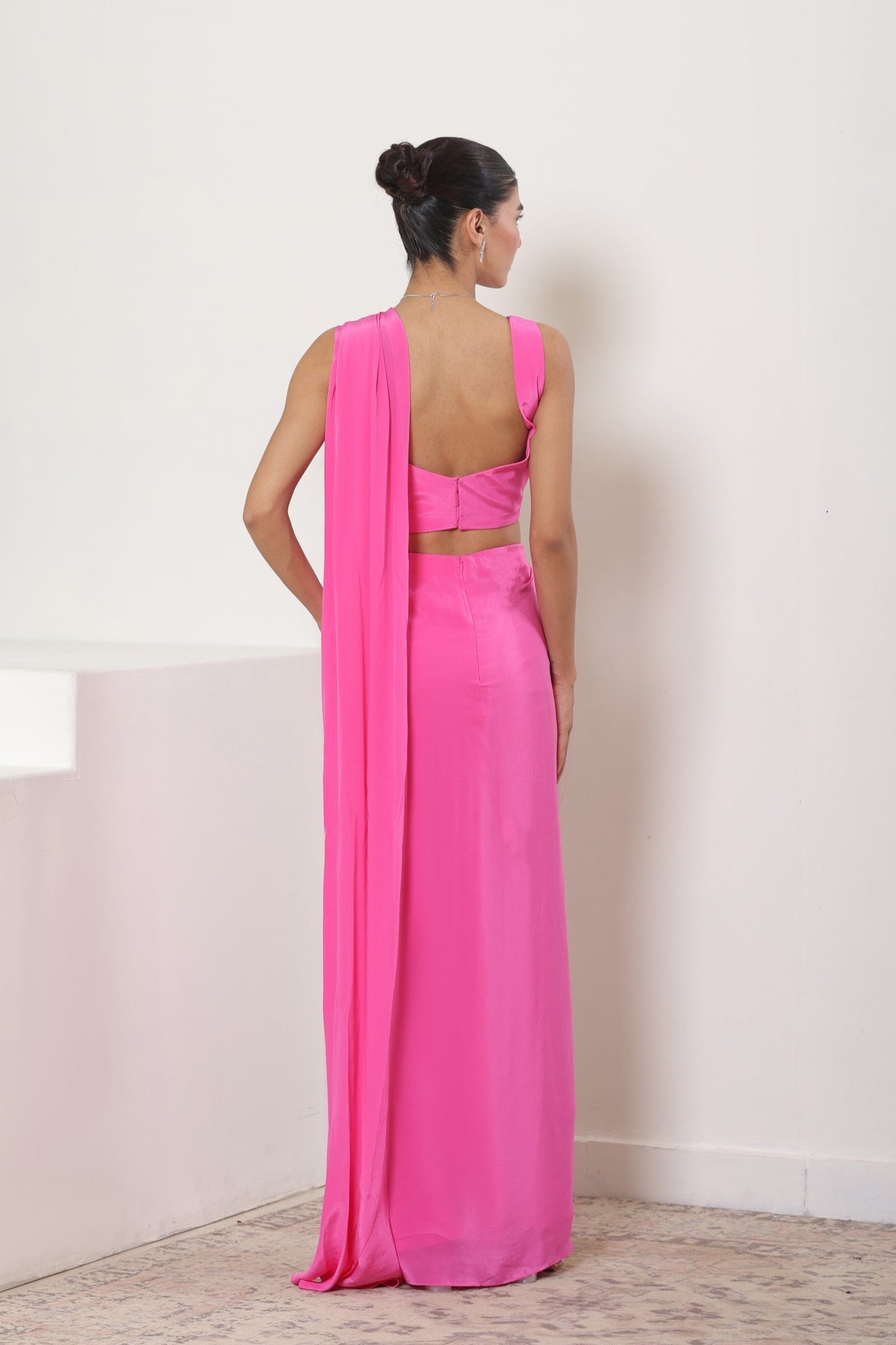 Woman wearing a bright pink saree with a matching blouse against a white background; Pink crepe saree, embroidered cocktail saree, premium party wear saree, designer festive outfit, elegant evening saree, Sunanta Madaan