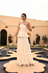 Elegant ivory sharara set featuring an off-shoulder corset-style blouse, perfect for a stylish Haldi ceremony or a vibrant sangeet celebration. The ensemble includes a corset sharara, making it an ideal choice for engagement parties or weddings. This exquisite sharara with corset design offers a blend of traditional charm and modern flair, making it a standout outfit for any special occasion. Sunanta Madaan