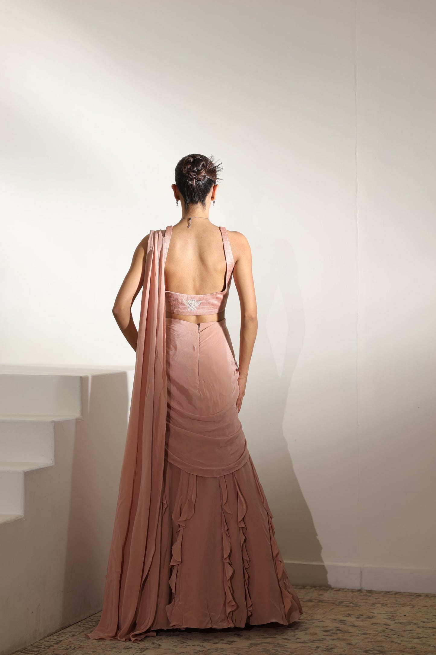 Woman wearing a pink evening gown with a sheer overlay against a plain background; Sunanta Madaan – Mocha Mousse Crepe Embroidered Drape Lehenga Saree, Premium Festive Wear, Elegant Party Outfit, Boho Indo-Western Dress, Indo-Western Fusion Wear, Indo-Western Attire for Engagement, Indo-Western Outfit for Sangeet, Indo-Western Draped & Embroidered Skirt, Women’s Designer Festive Ensemble, Delhi, Jaipur, Hyderabad, Ahmedabad, Bangalore, near me