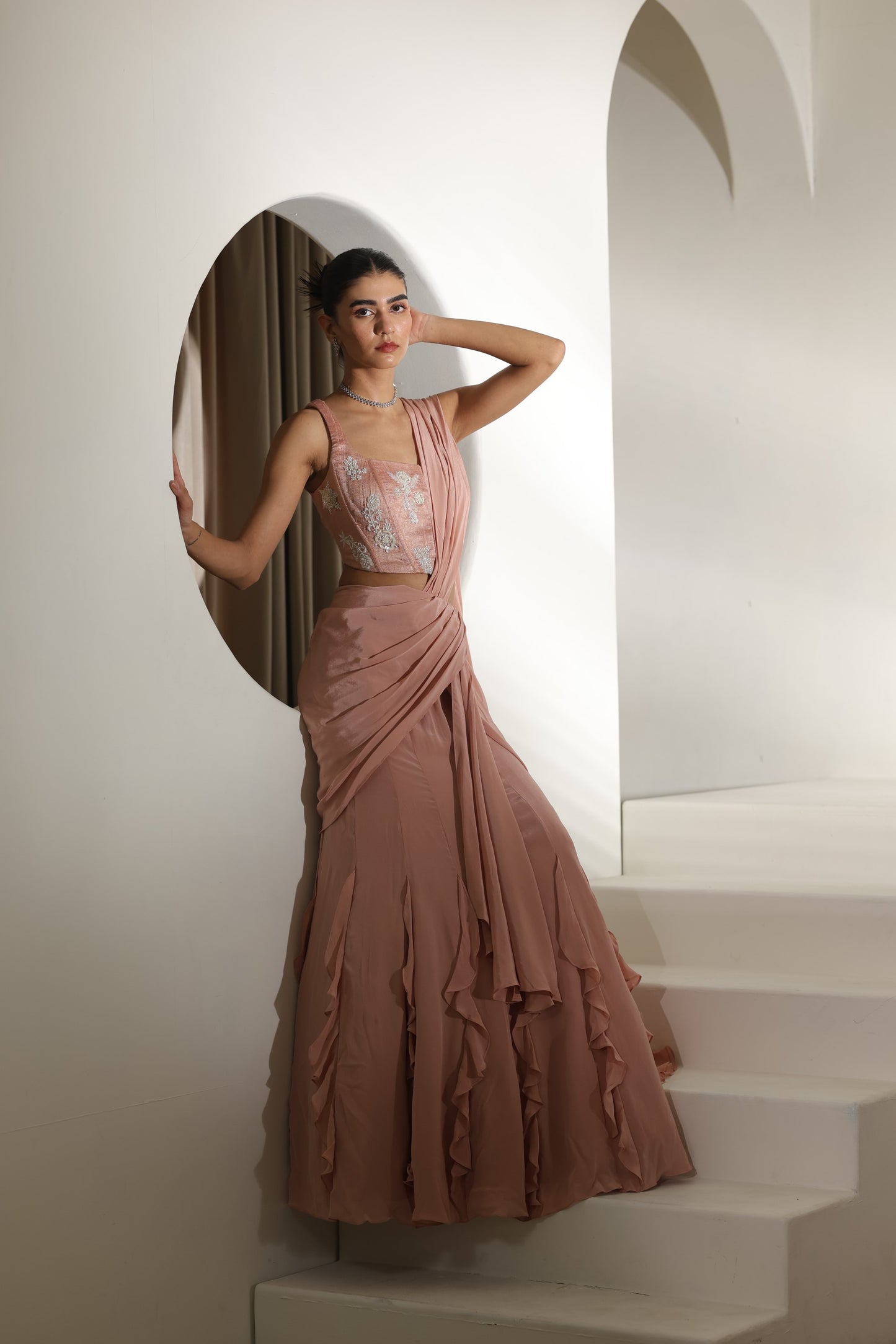 Woman in a elegant dress standing on a staircase with a neutral background; Sunanta Madaan – Mocha Mousse Crepe Embroidered Drape Lehenga Saree, Premium Festive Wear, Elegant Party Outfit, Boho Indo-Western Dress, Indo-Western Fusion Wear, Indo-Western Attire for Engagement, Indo-Western Outfit for Sangeet, Indo-Western Draped & Embroidered Skirt, Women’s Designer Festive Ensemble, Delhi, Jaipur, Hyderabad, Ahmedabad, Bangalore, near me