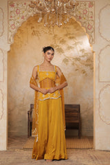 Woman in a yellow traditional outfit standing in an ornate room with a chandelier. Yellow silk crepe sharara, festive ethnic outfit, elegant occasional wear, designer traditional attire, premium party ensemble, Sunanta Madaan, near me, Mumbai, Delhi, Hyderabad, Bangalore, Pune