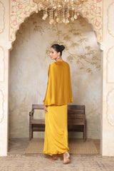 Woman in a yellow outfit standing in an ornate room with a chandelier. Yellow crepe kaftan, V-neck embroidered kaftan, handcrafted festive outfit, elegant ethnic wear, designer party kaftan, Sunanta Madaan